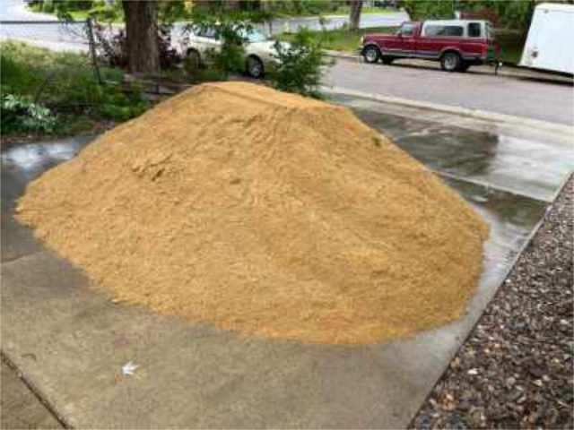 a photo of a dump truck dumping washed concrete sand onto a paved path
